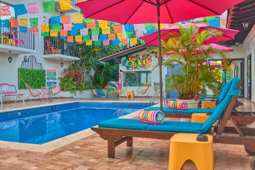 a pool with two lounge chairs and an umbrella at Casa Maria Hotel Boutique & Gallery Adults Only in Puerto Vallarta