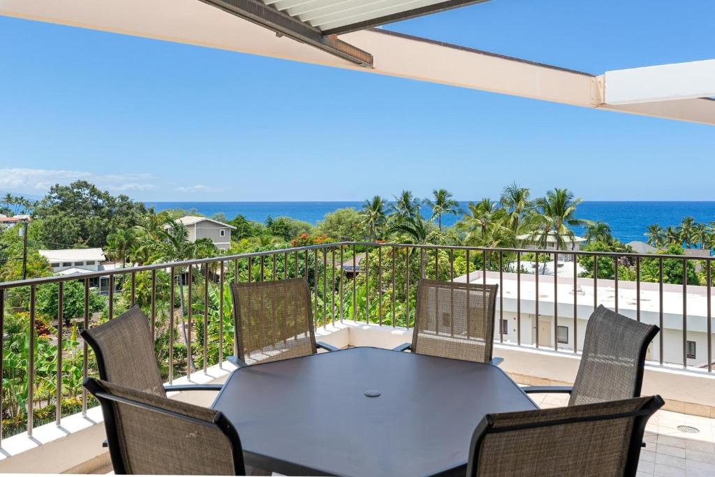 een patio met een tafel en stoelen op een balkon bij Big Island Royal Sea Cliff 705 condo in Kailua-Kona