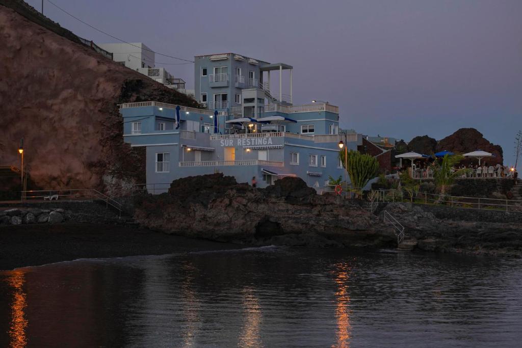 una gran casa azul en un acantilado junto al agua en Sur Restinga, en La Restinga