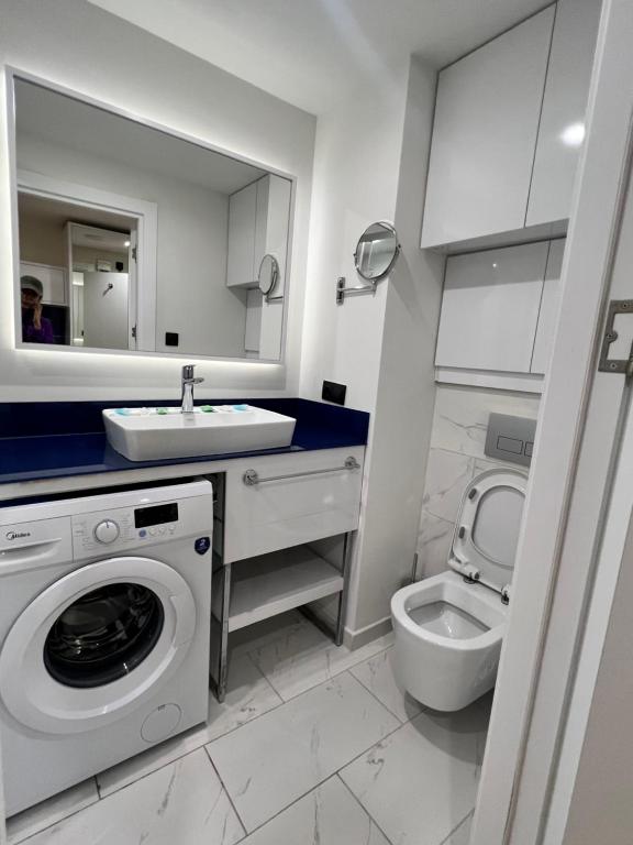 a bathroom with a washing machine and a toilet at Orbi City apartment with sea view in Batumi