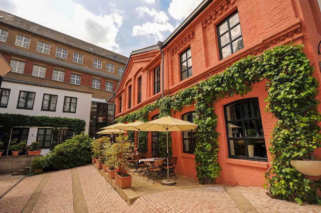 - un bâtiment en briques avec une table et un parasol dans l'établissement Domicil Hotel Bonn, à Bonn