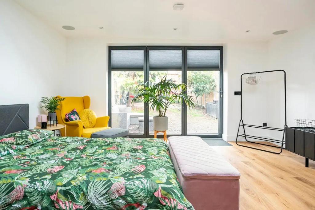 1 dormitorio con 1 cama grande y 1 silla amarilla en Modern Studio with parking in private garden, en Theydon Bois