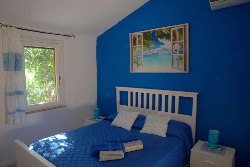 Dormitorio azul con cama y ventana en sea ottiolu, en Porto Ottiolu