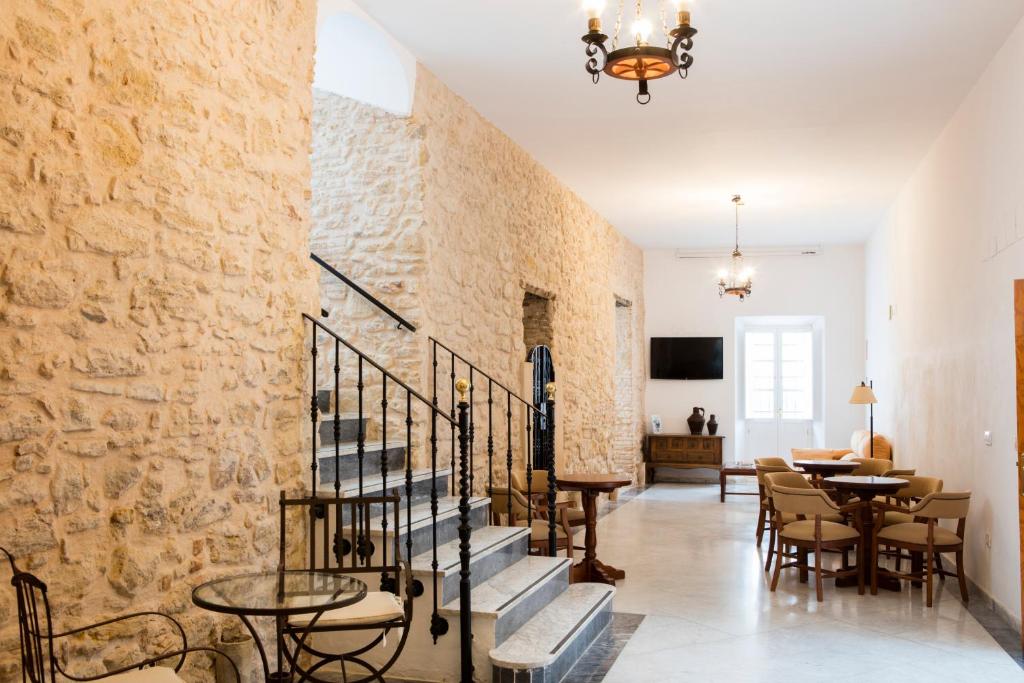 Habitación con escaleras, mesas y pared de piedra. en Hotel Tugasa Casa Palacio Medina Sidonia, en Medina Sidonia