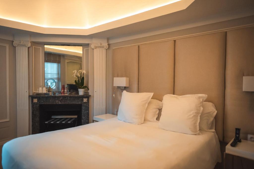 a bedroom with a bed with white pillows and a fireplace at Clarance Hotel Lille in Lille