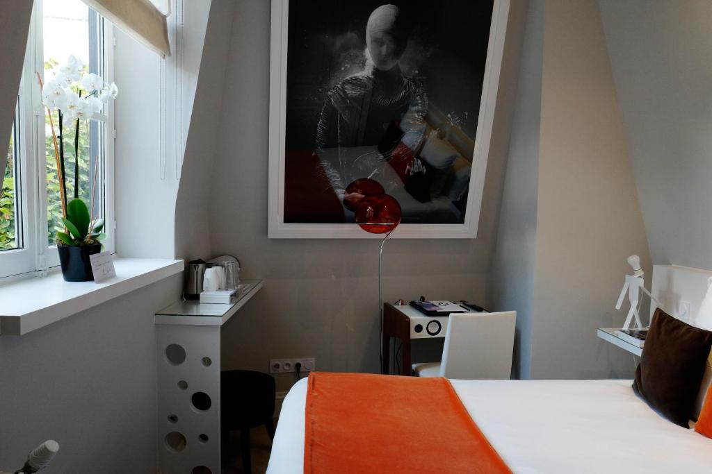 a bedroom with a bed and a picture on the wall at Clarance Hotel Lille in Lille