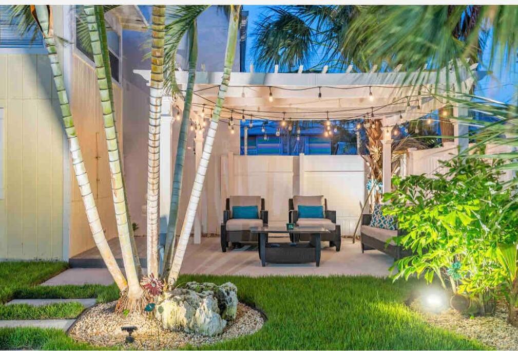 un patio con mesa, sillas y palmeras en Lovely 2 bedrooms, steps away from the beach., en Bradenton Beach