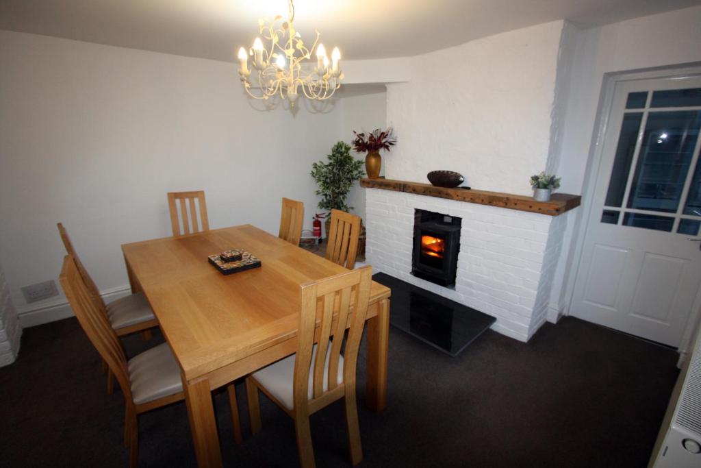a dining room with a table and a fireplace at Lymm Cottage in Lymm