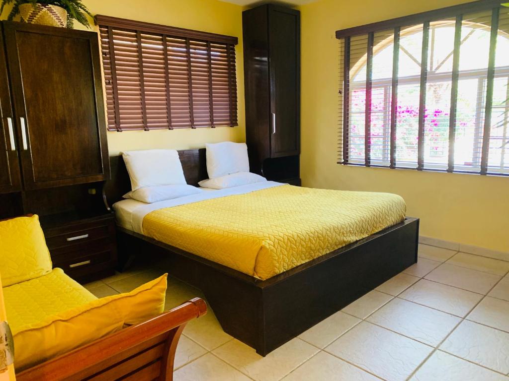 a bedroom with a bed with yellow walls and windows at Casa Opal in Palm-Eagle Beach