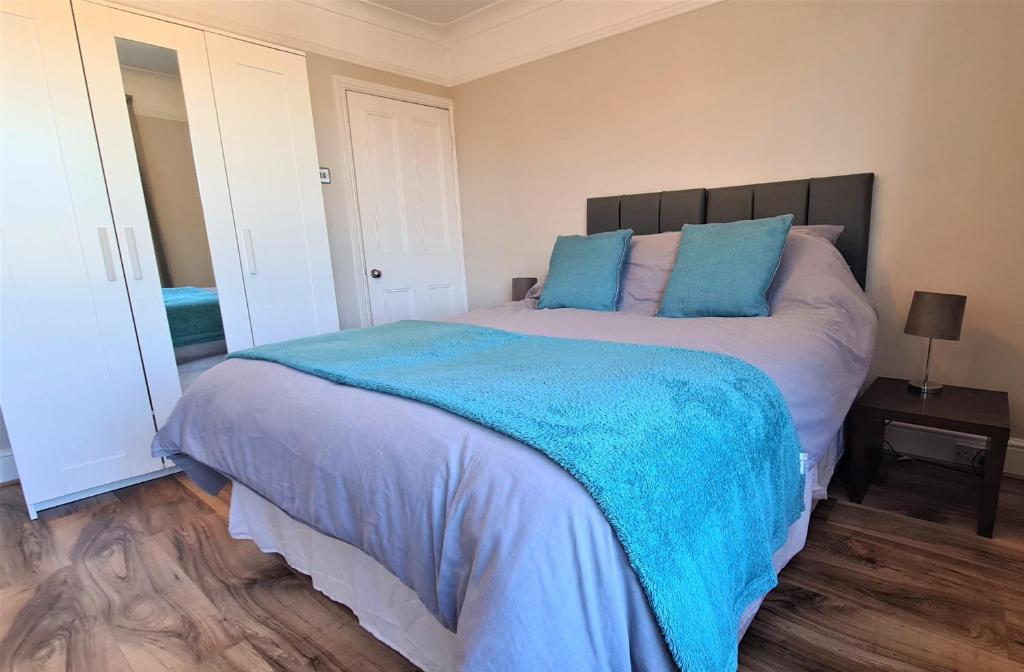 a bedroom with a large bed with blue pillows at Castle Cottage in Rayleigh
