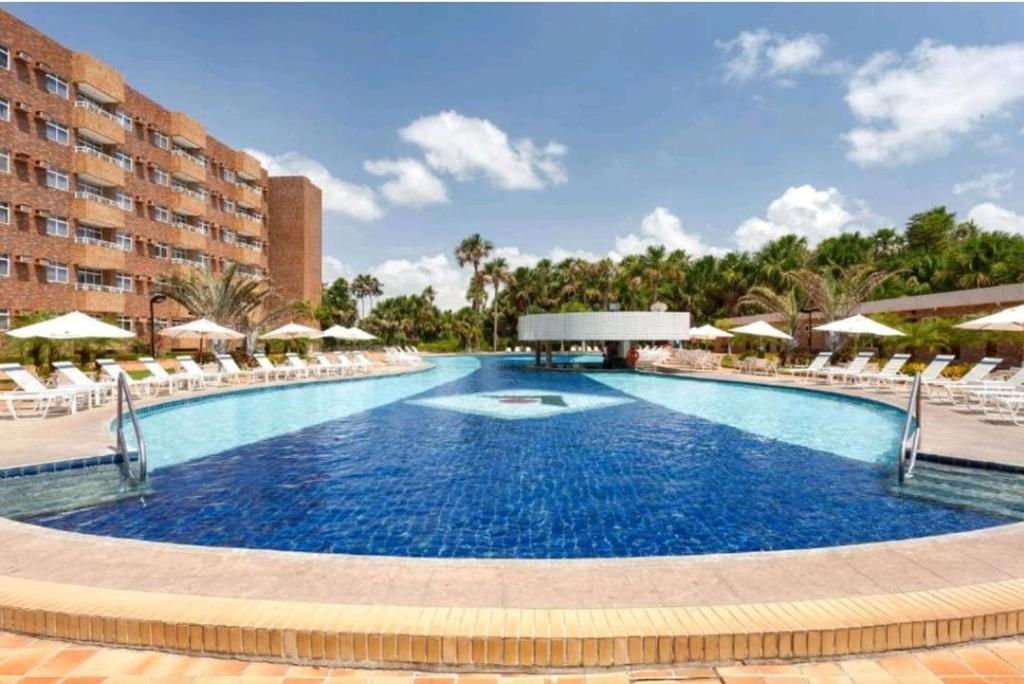 einen großen Pool mit Stühlen und Sonnenschirmen in einem Resort in der Unterkunft Gran Lençóis Flat Residen in Barreirinhas