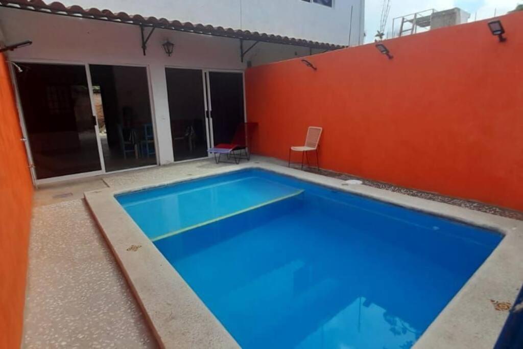 a large blue swimming pool with a red wall at C911 Casa 2 niveles y alberca privada in Peñita de Jaltemba
