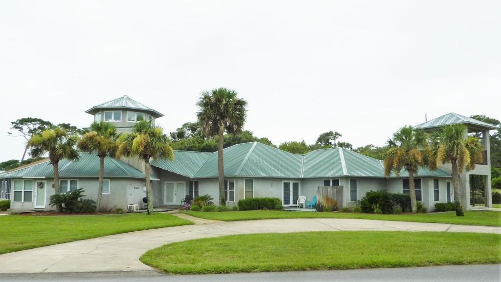 a large house with palm trees in front of it at GUIDING LIGHT UNIT C - GROUNDFLOOR apts in Jekyll Island