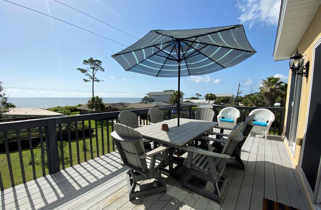 a table and chairs with an umbrella on a deck at THE SALTY SOL home in Jekyll Island