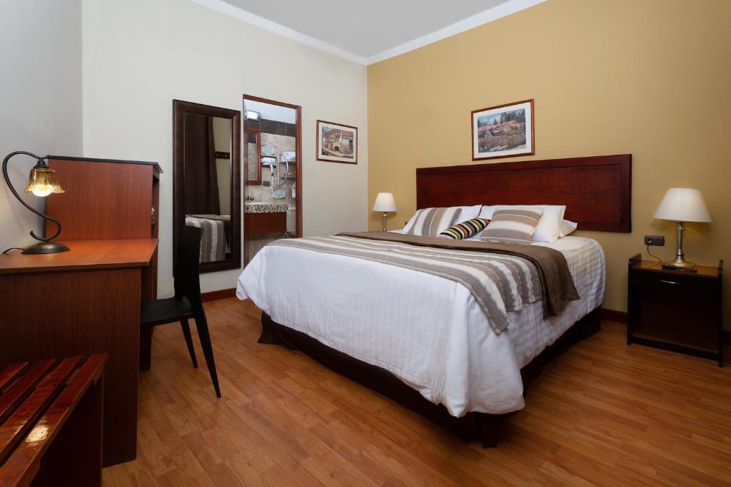 um quarto com uma cama grande, uma secretária e uma cama lateral. em Casa de Avila em Arequipa