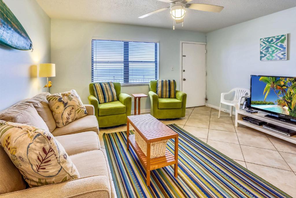 a living room with a couch and a tv at Sunset Chateau 207 in St Pete Beach