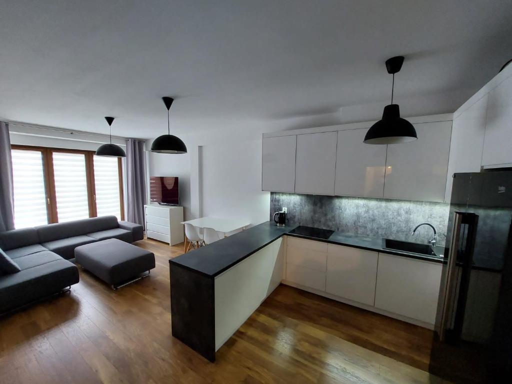 cocina con armarios blancos y sala de estar. en Apartament Reformacka en Wieliczka