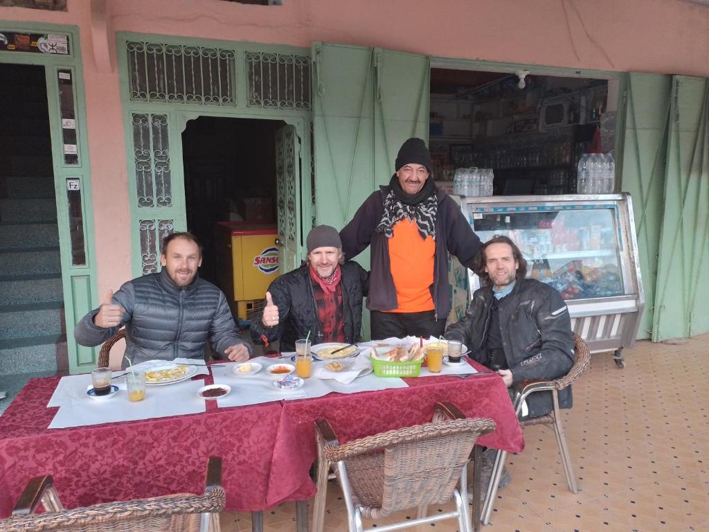 un grupo de hombres sentados en una mesa comiendo comida en Auberge Restaurant Rooftop Tamazirt, en Boumalne