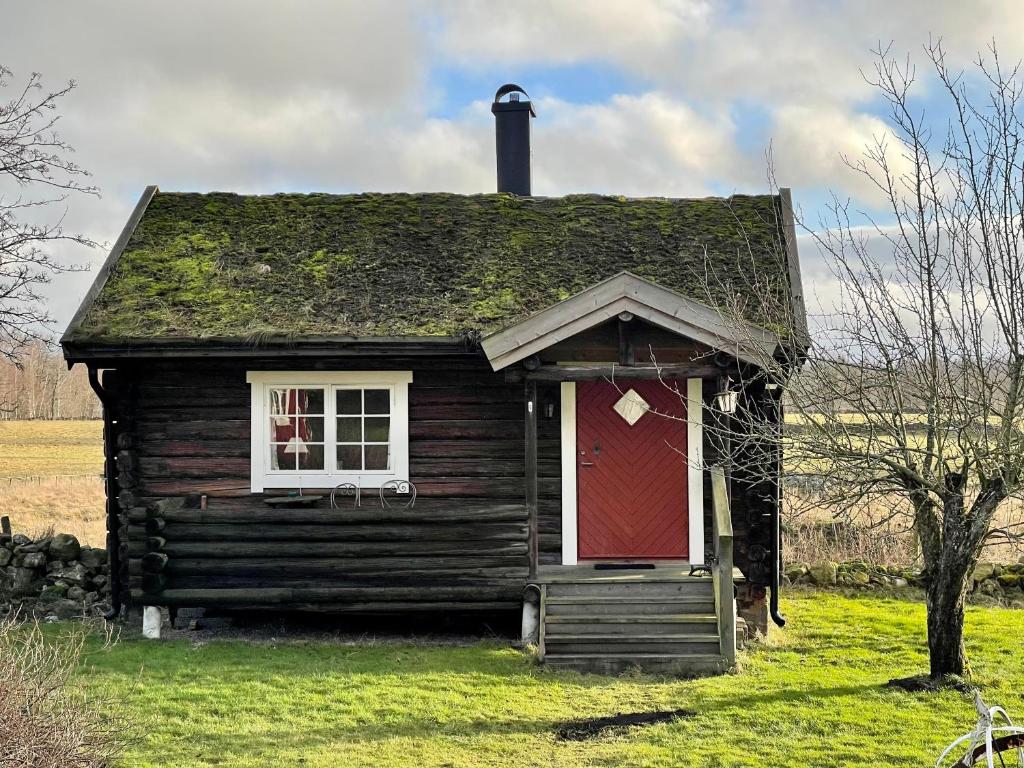 una casa antigua con una puerta roja y una ventana en Backgårdens Timmerstuga en Falköping