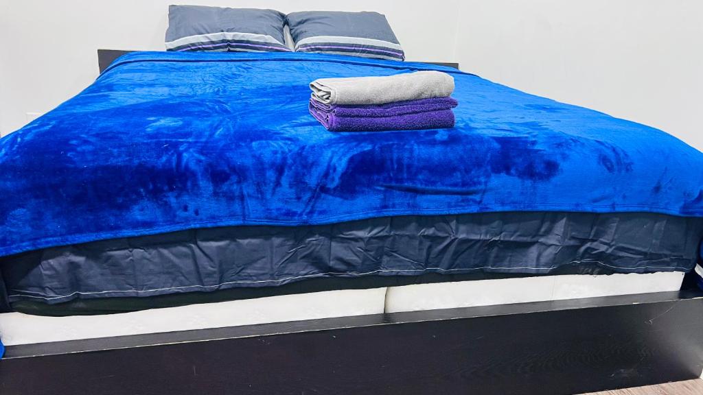 a blue bed with two towels on top of it at The Home Sweet Home in Winnipeg