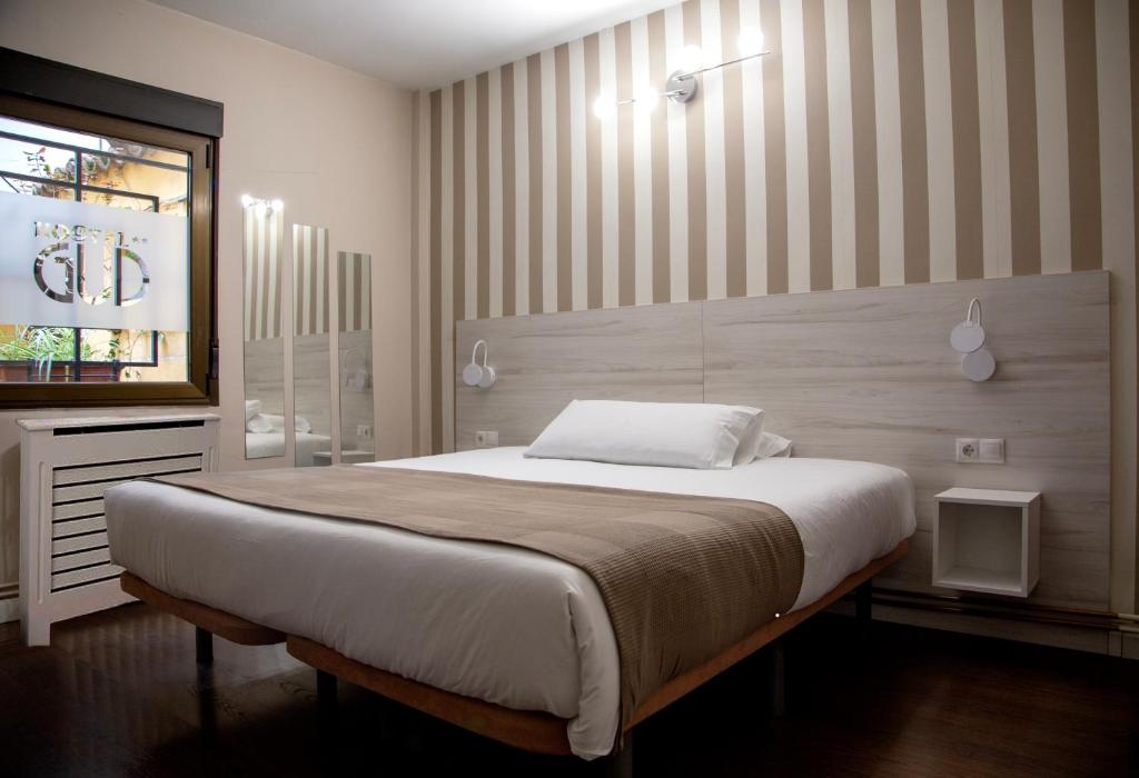 a bedroom with a large bed with a striped wall at Hostal Gud Salamanca in Salamanca