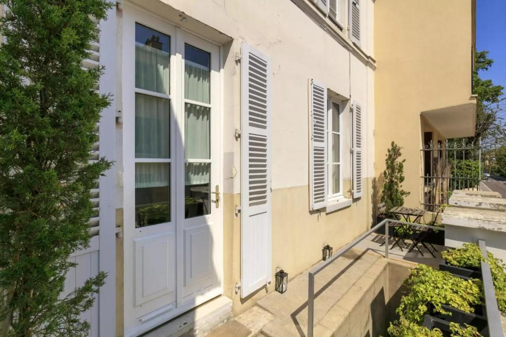 Cette maison dispose d'une porte blanche et d'un balcon. dans l'établissement La Terrasse de Mademoiselle, à Versailles