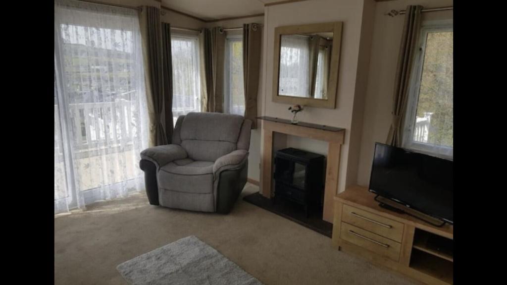 a living room with a chair and a television at Large and comfortable, stylish caravan. in Bembridge
