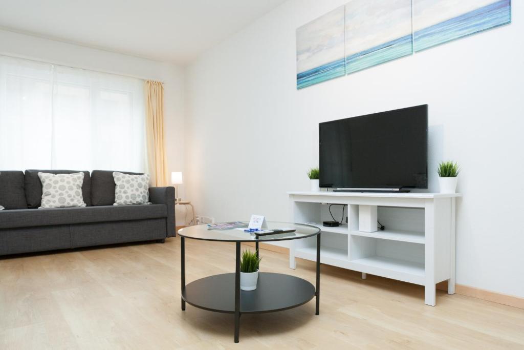 a living room with a black couch and a tv at Galaxy Apartments Lucerne in Luzern