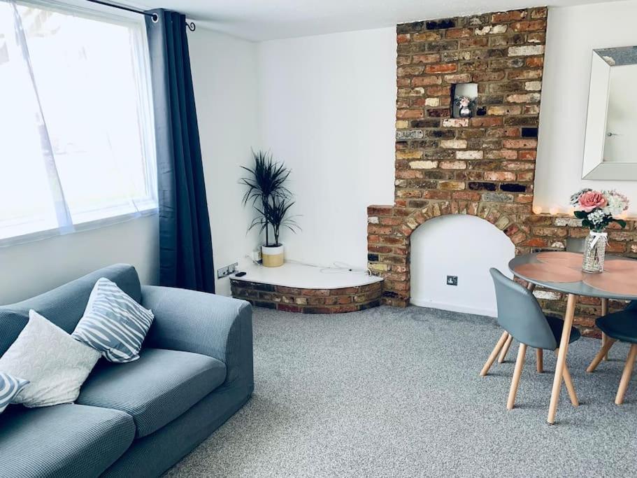 een woonkamer met een bank en een stenen open haard bij Aylesbury Apartment for Contractors and Holidays in Aylesbury