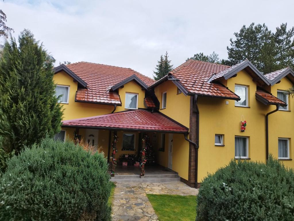 a yellow house with a red roof at Apartmani Jokic in Zlatibor