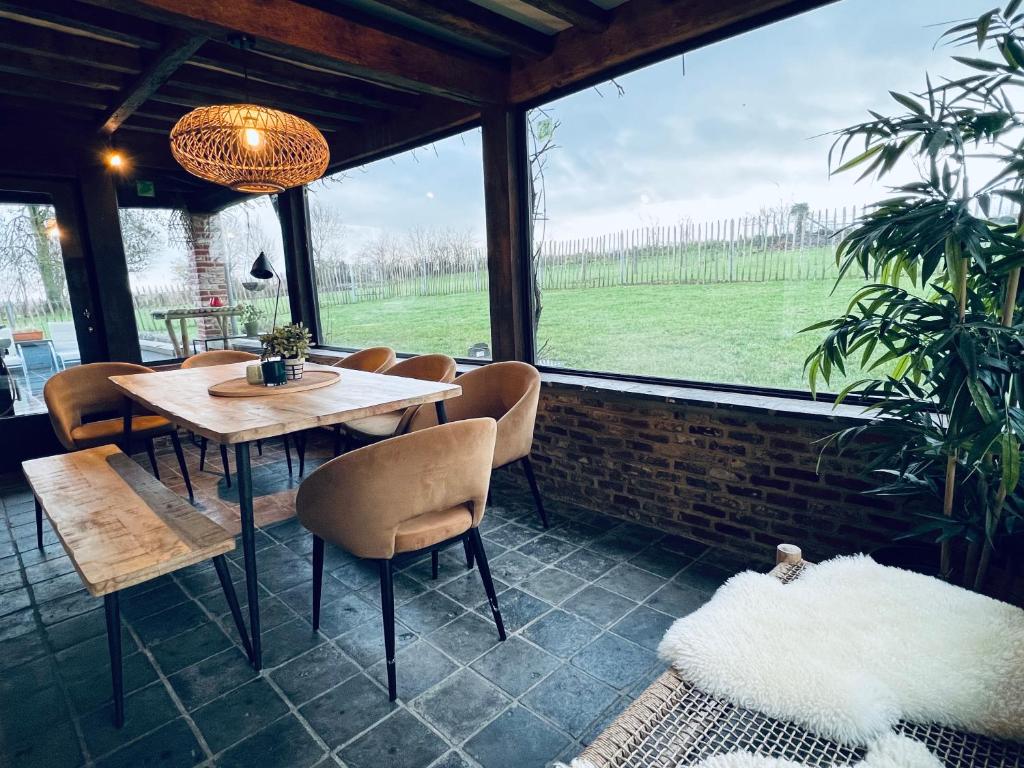 une salle à manger avec une table, des chaises et une grande fenêtre dans l'établissement ZEN op Vakantie - Zen in de Vlaamse Ardennen Sint Janshoeve, 