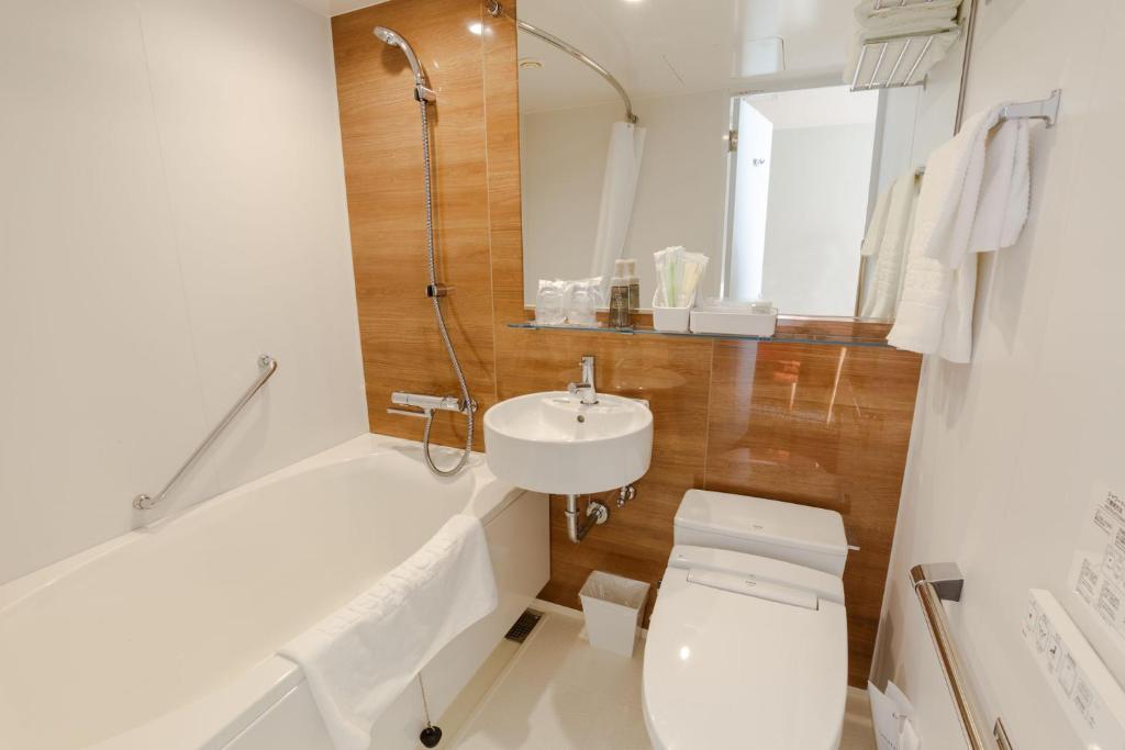 a bathroom with a toilet and a sink and a bath tub at Keisei Hotel Miramare in Chiba