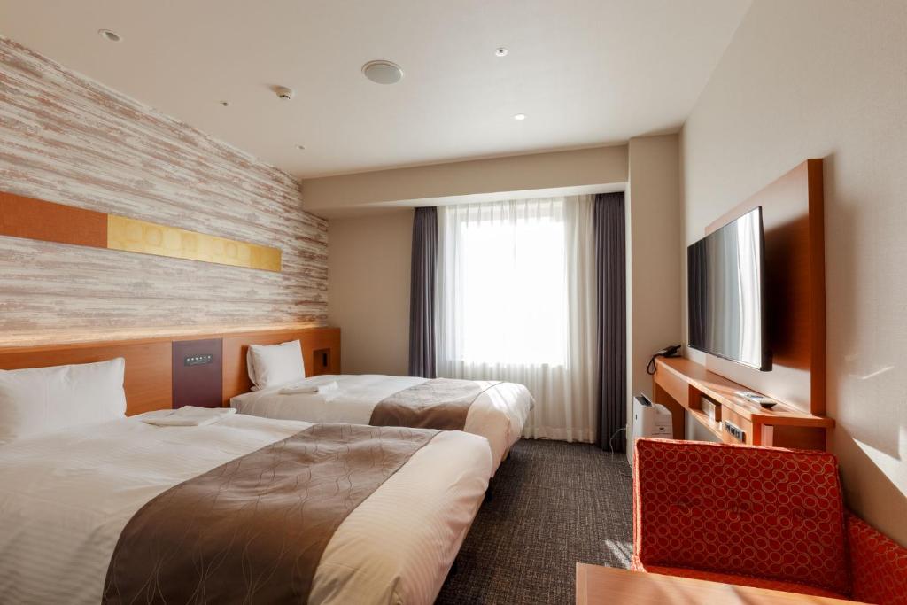 um quarto de hotel com duas camas e uma televisão de ecrã plano em Keisei Hotel Miramare em Chiba