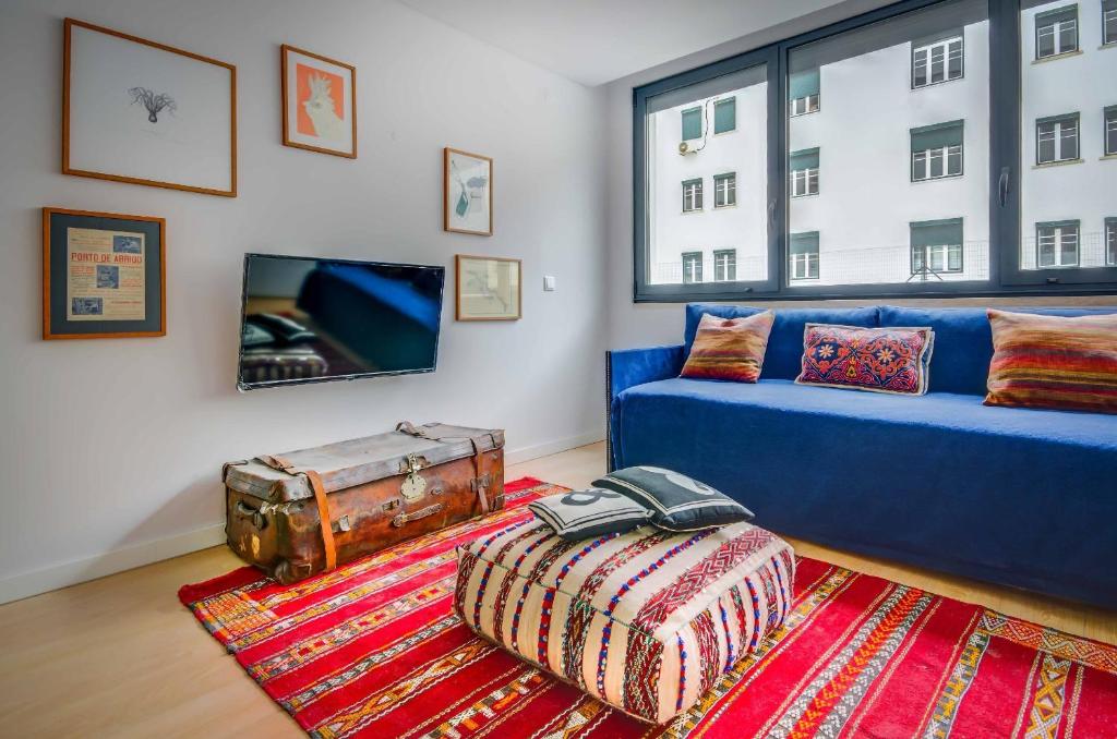 a living room with a blue couch and a large window at Lisbon Serviced Apartments - Liberdade in Lisbon