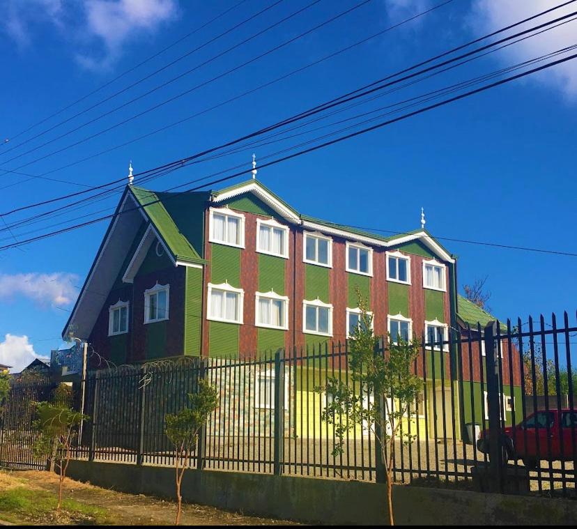 a large red and green house behind a fence at Hotel Casona Los Colonos in Valdivia