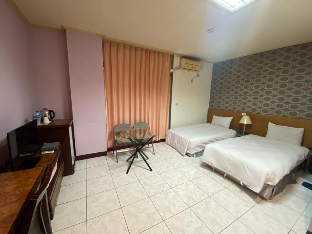 a hotel room with two beds and a television at Jiuning Business Hotel in Tainan