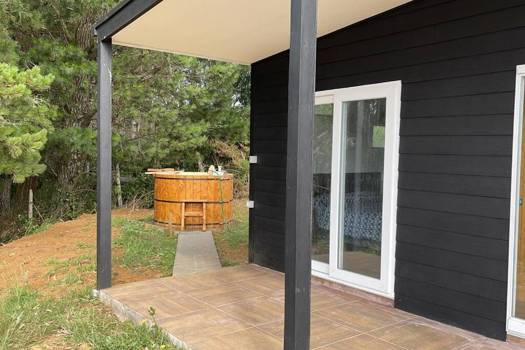 a black house with a wooden patio with a tub at Cabañas Borde Lindo in Valdivia