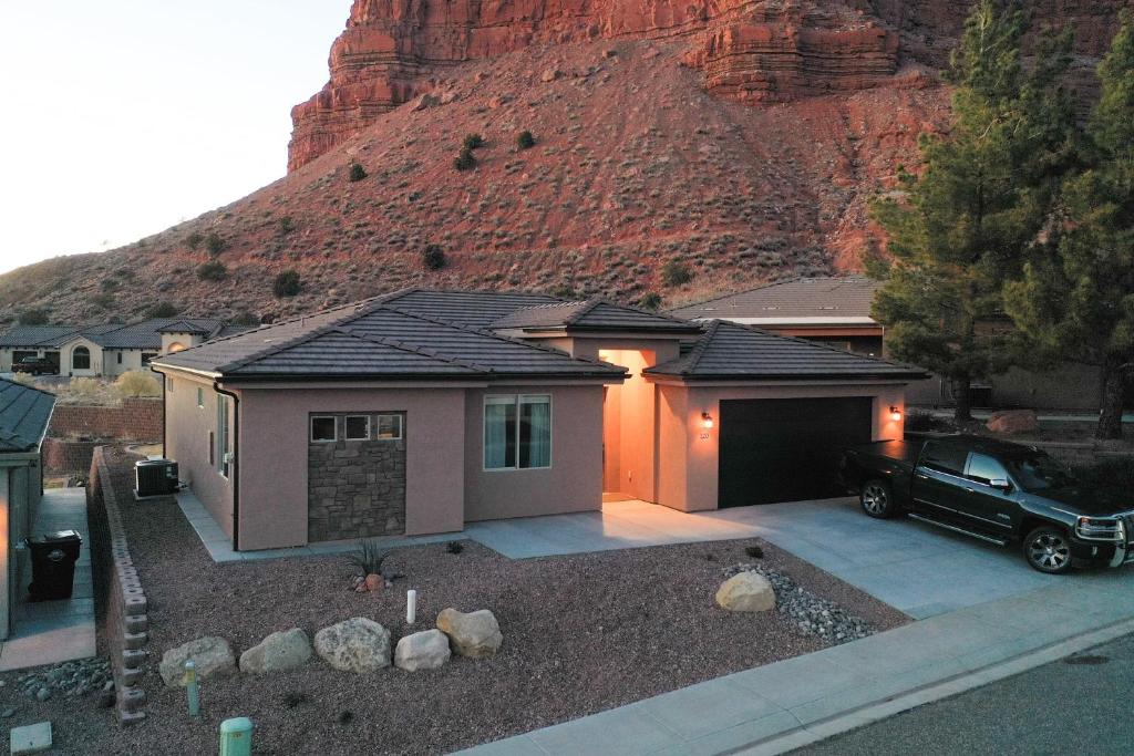 a house with a car parked in front of a mountain at Searchers Hideaway at Kabab - New West Properties in Kanab