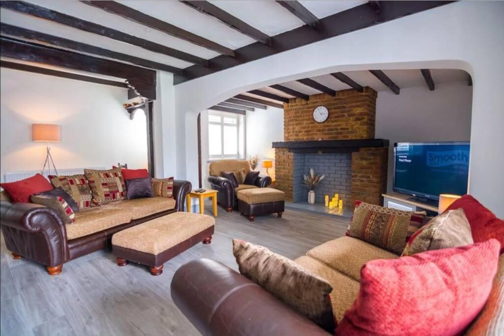 ein Wohnzimmer mit Sofas, einem TV und einem Kamin in der Unterkunft A Bright and Spacious Gem-Newly renovated house in Staines