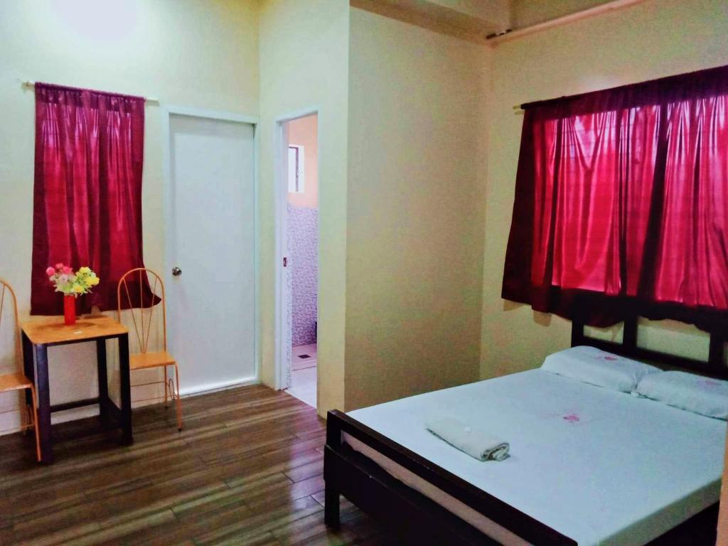 a bedroom with a bed with a red curtain at WJV INN CONSOLACION in Consolation