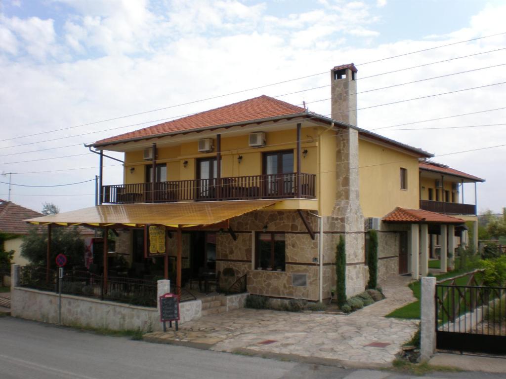 een geel huis met een balkon in een straat bij Olympia Guesthouse in Vergina