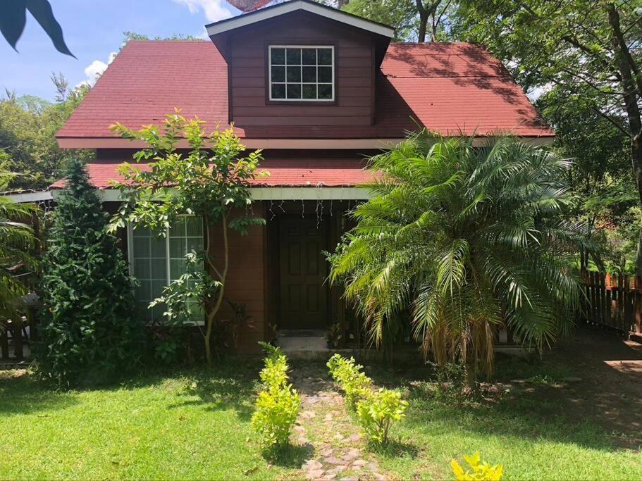 une maison avec un toit rouge et une cour verdoyante dans l'établissement Cabaña de las Flores. Magia en la laguna, à Santa María del Oro