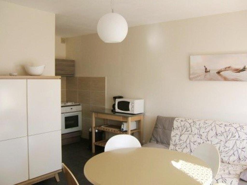 Il comprend un petit salon avec une table et une cuisine. dans l'établissement Charmant T2 avec terrasse et parking privé, proche plage, capacité 4 personnes - Marseillan - FR-1-326-495, à Marseillan