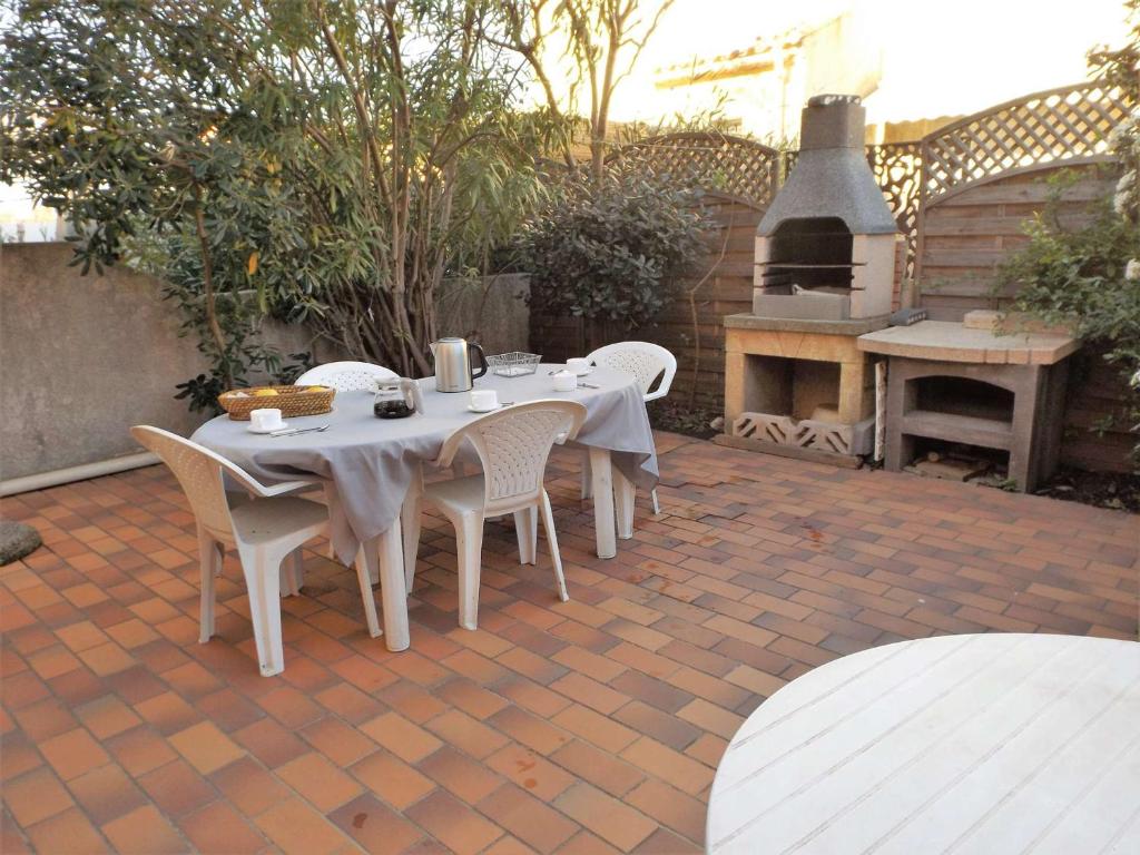 - une table et des chaises sur une terrasse avec un four extérieur dans l'établissement Villa Mitoyenne 6 Pers avec Terrasse, BBQ, Parking et WIFI à Grau d'Agde - FR-1-423-179, au Grau-dʼAgde
