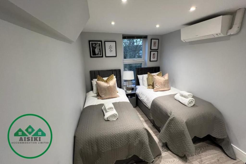 Dwa łóżka w małym pokoju z pokojem z w obiekcie Aisiki Apartments at Stanhope Road, North Finchley, Multiple 2 or 3 Bedroom Pet Friendly Duplex Flats, King or Twin Beds with Aircon & FREE WIFI w mieście Finchley