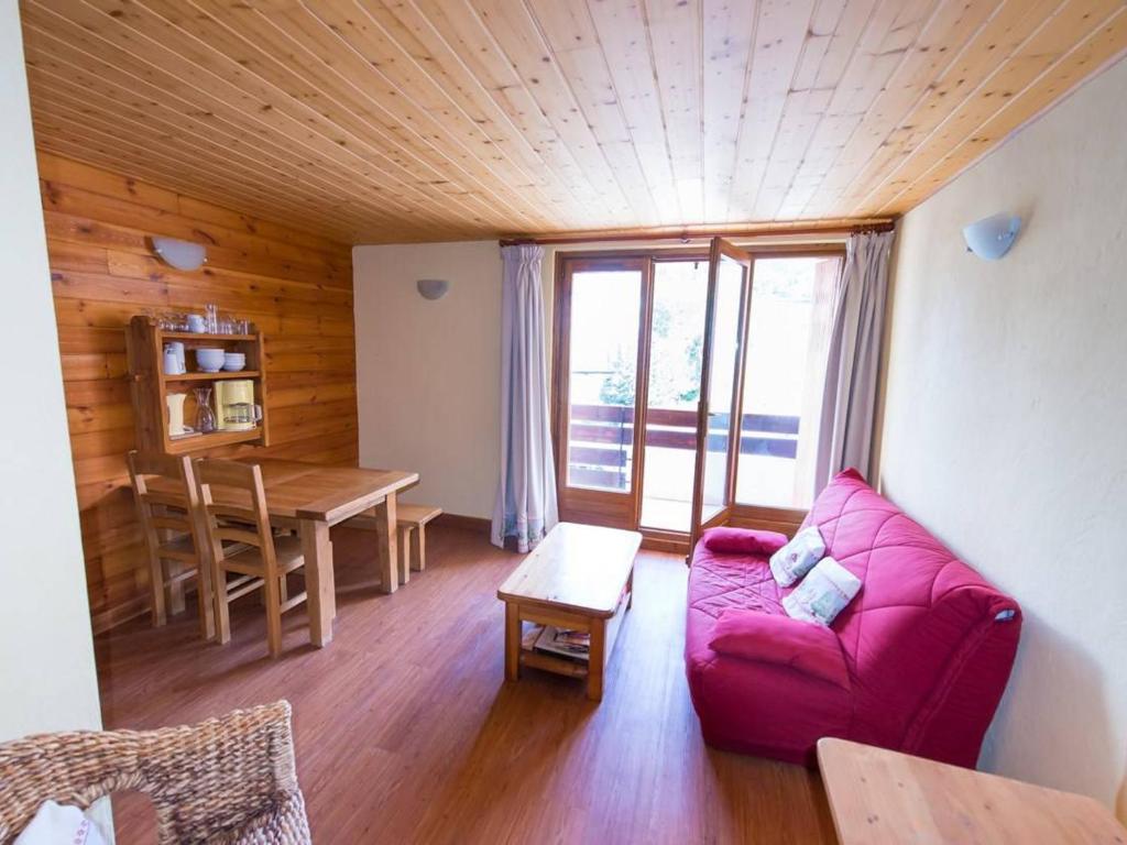 a living room with a red couch and a table at Appartement Serre Chevalier, 1 pièce, 4 personnes - FR-1-330F-119 in Serre Chevalier