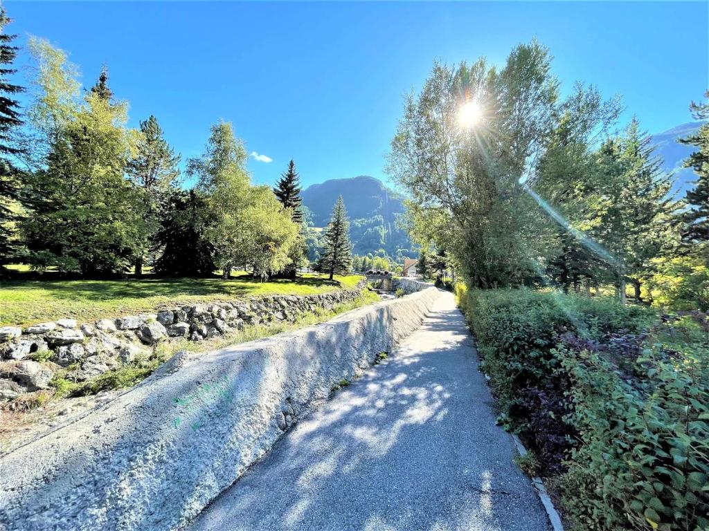 a dirt road with trees and a stone wall at Appartement Serre Chevalier, 1 pièce, 4 personnes - FR-1-330F-119 in Serre Chevalier