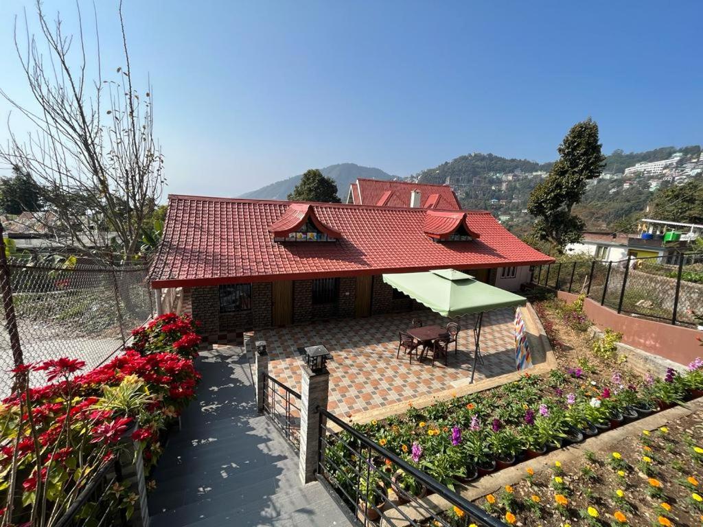 Hidden Cottage في Namchi: منزل بسقف احمر وبعض الزهور