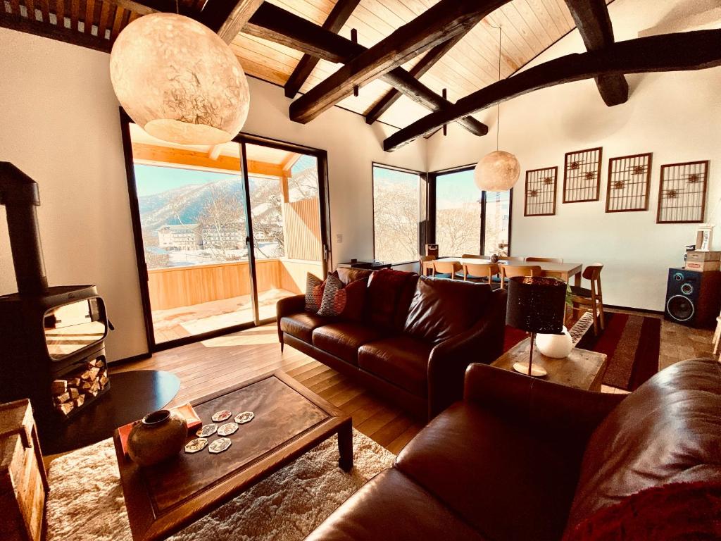 a living room with leather couches and a table at Snowman Apartments at Madarao Mountain in Iiyama