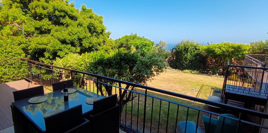 een balkon met een tafel en stoelen en uitzicht op een park bij The Zen Den in Durban